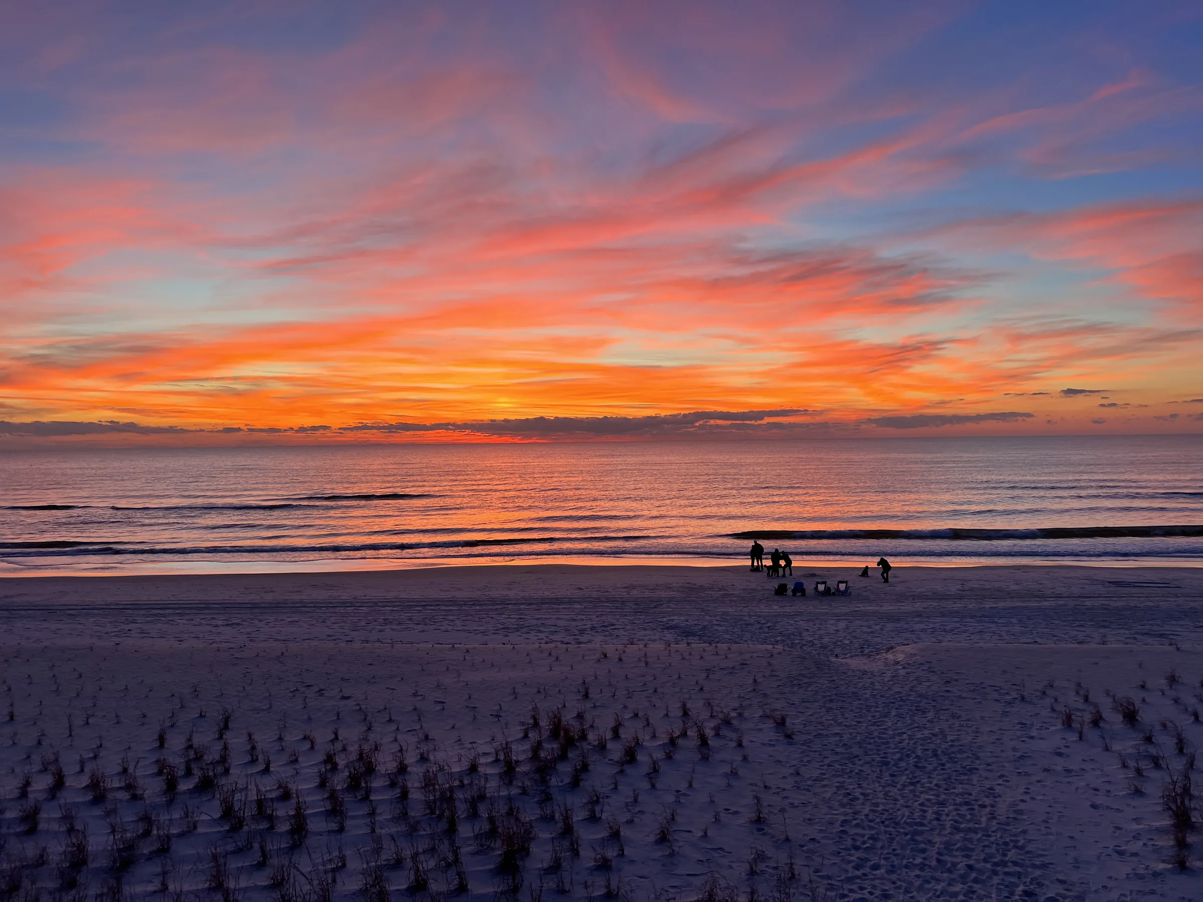 Sunset over the Gulf with people walking dogs on the beach at Indian Pass
